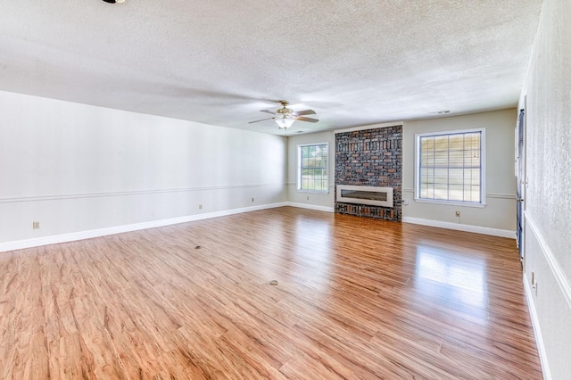 301 W Paul Ave, Clovis, CA 93612 - unfurnished living room featuring a brick fireplace, a ceiling fan, a textured ceiling, and light wood-style floors