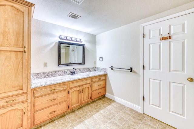 301 W Paul Ave, Clovis, CA 93612 - bathroom featuring a textured ceiling, visible vents, baseboards, and vanity