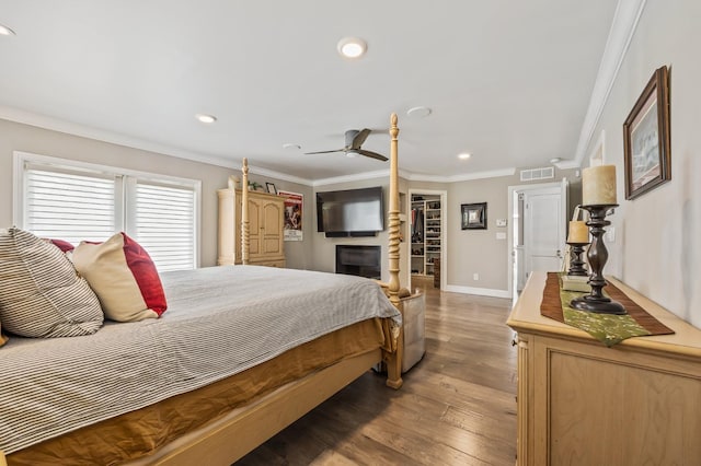 bedroom with crown molding, visible vents, wood finished floors, baseboards, and recessed lighting