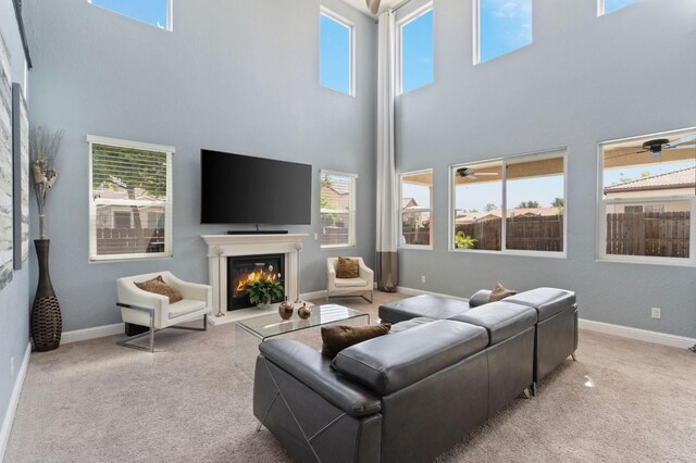 living area with carpet flooring, a lit fireplace, and a towering ceiling