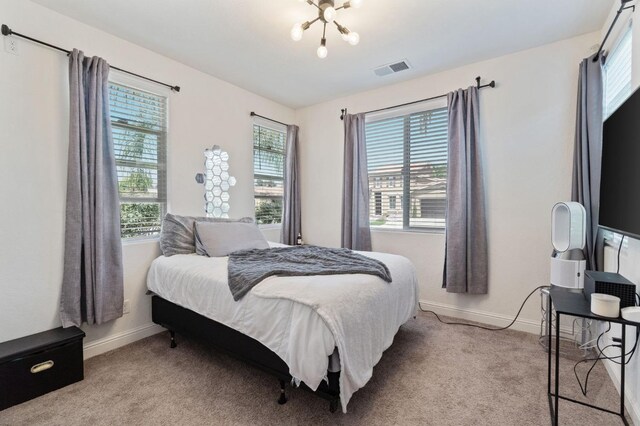 carpeted bedroom featuring baseboards, visible vents, and multiple windows