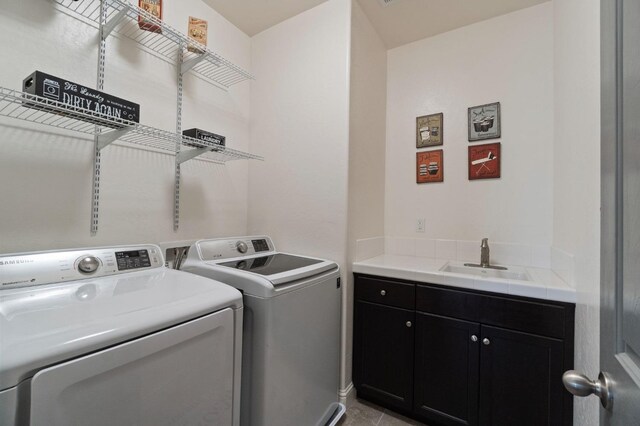 clothes washing area with cabinet space, washer and clothes dryer, and a sink