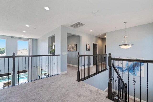 hallway featuring visible vents, carpet floors, baseboards, recessed lighting, and an upstairs landing