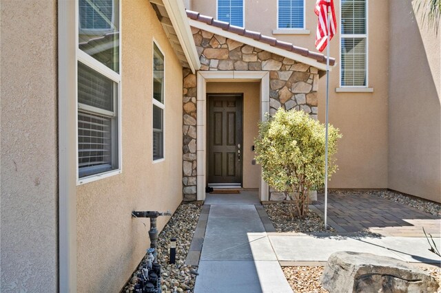 doorway to property with stone siding and stucco siding