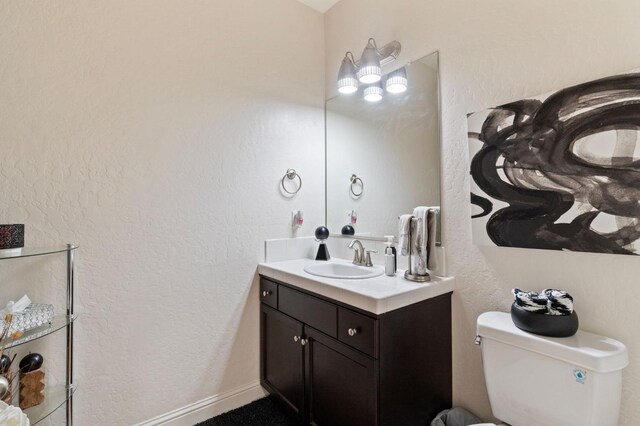bathroom featuring vanity, a textured wall, and toilet