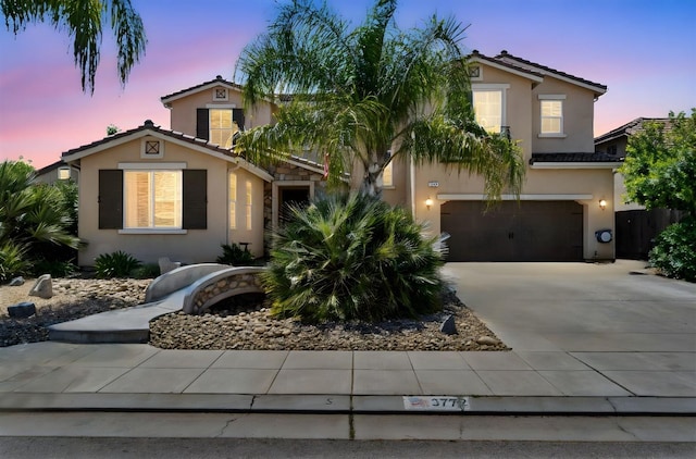 mediterranean / spanish-style home with a tiled roof, a garage, driveway, and stucco siding