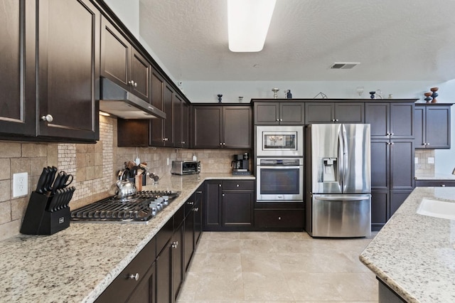 3772 Wrenwood Ave, Clovis, CA 93619 - kitchen with under cabinet range hood, visible vents, dark brown cabinetry, stainless steel appliances, and tasteful backsplash