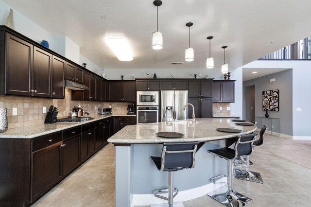 kitchen featuring a sink, stainless steel appliances, tasteful backsplash, under cabinet range hood, and visible vents