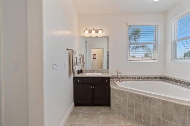 bathroom with vanity, tile patterned flooring, baseboards, and a bath