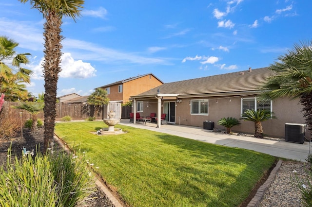 rear view of property featuring fence, cooling unit, a yard, a patio, and stucco siding