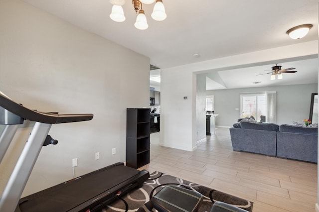 exercise room featuring baseboards and ceiling fan with notable chandelier