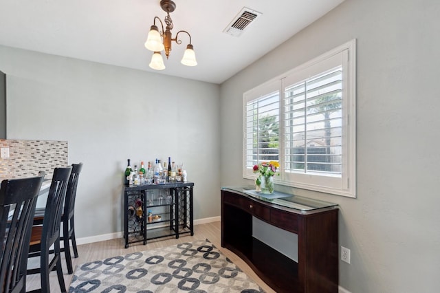 dining space with visible vents, light wood-style flooring, baseboards, and an inviting chandelier
