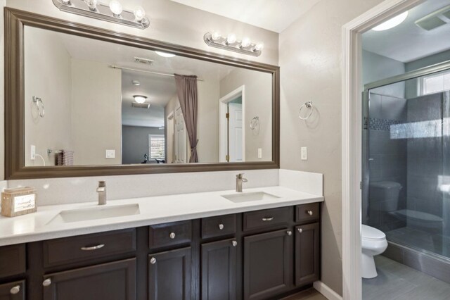 full bath with a sink, a stall shower, toilet, and double vanity