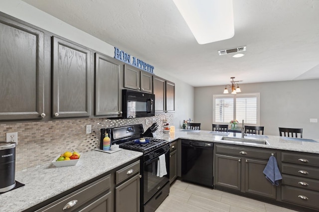 kitchen with a sink, decorative backsplash, black appliances, and visible vents