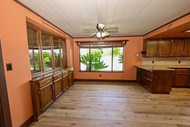 kitchen featuring ceiling fan, a peninsula, baseboards, decorative backsplash, and light wood-type flooring