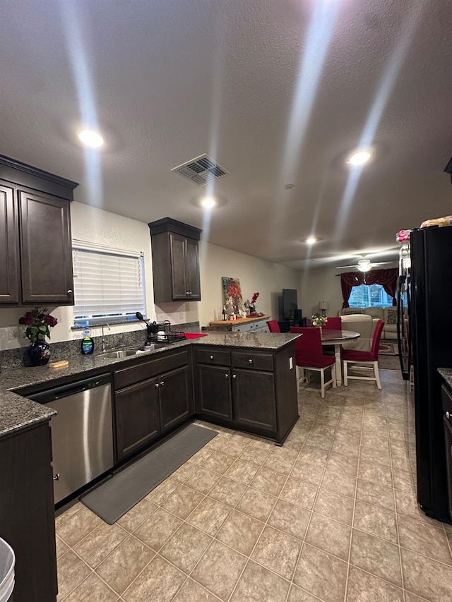 628 Marcus Ave, Merced, CA 95341 - kitchen with freestanding refrigerator, a peninsula, dark stone counters, stainless steel dishwasher, and visible vents