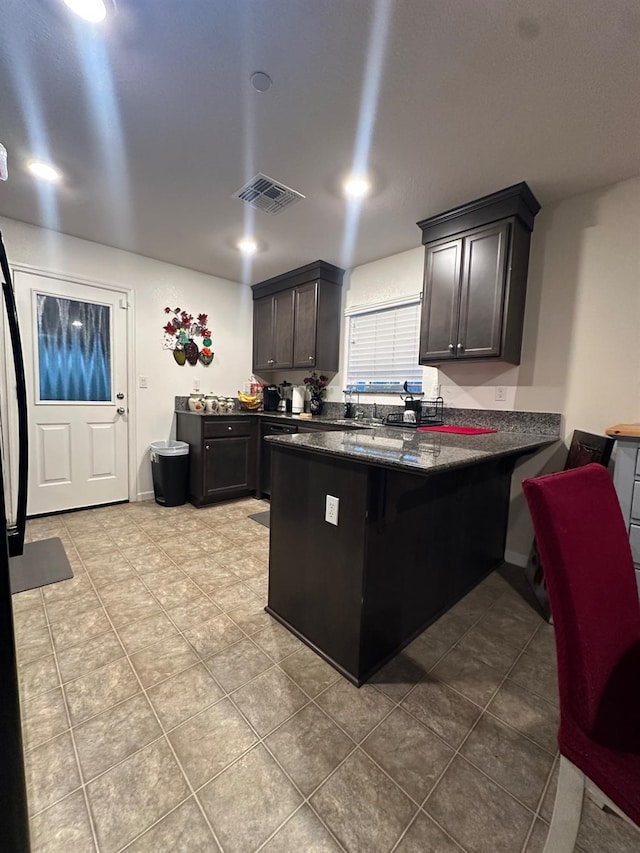 628 Marcus Ave, Merced, CA 95341 - kitchen with visible vents, tile patterned flooring, a peninsula, a kitchen bar, and dark stone countertops