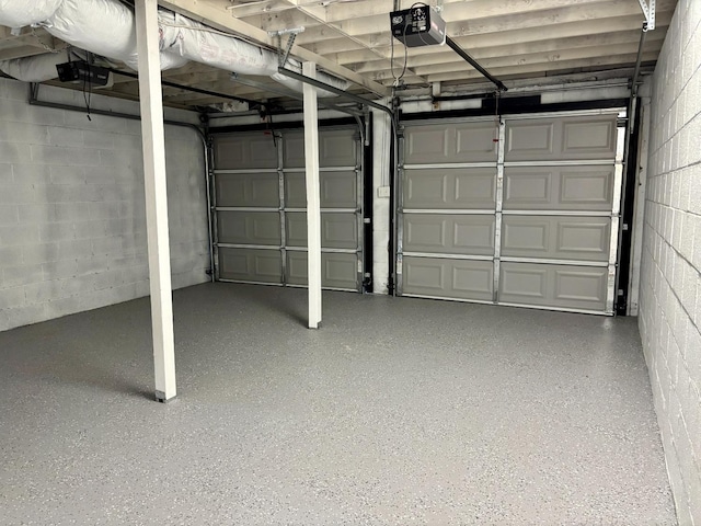 garage featuring concrete block wall and a garage door opener