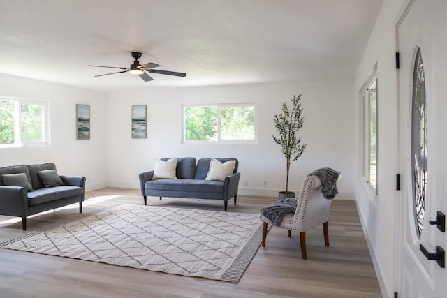 living area with baseboards, a ceiling fan, and wood finished floors