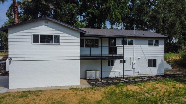 rear view of property featuring a lawn, a patio, central AC, and a balcony