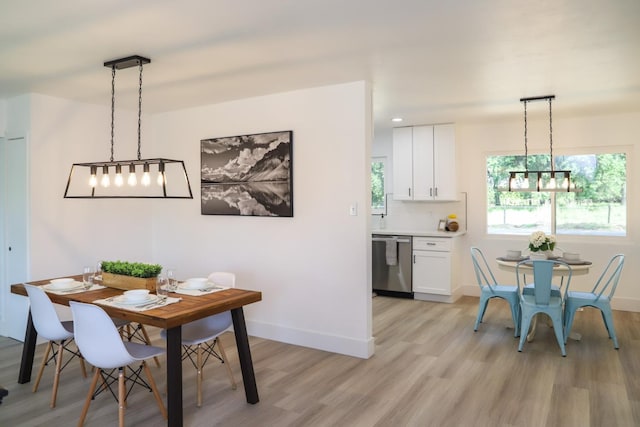 dining area featuring light wood-type flooring, baseboards, and an inviting chandelier