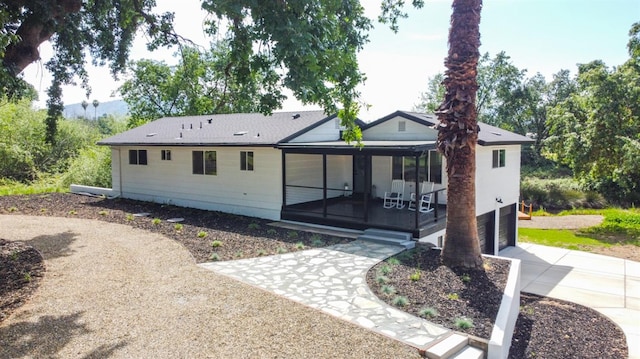 back of property featuring a garage, a sunroom, and driveway