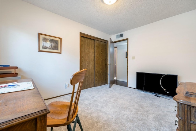 home office with visible vents, a textured ceiling, baseboards, and light colored carpet