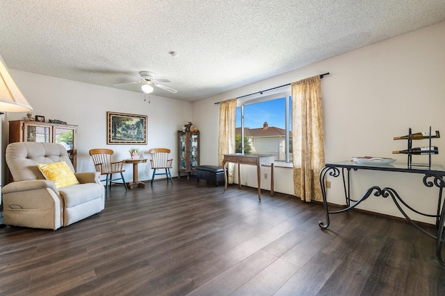 sitting room featuring ceiling fan, dark wood-style floors, and a textured ceiling