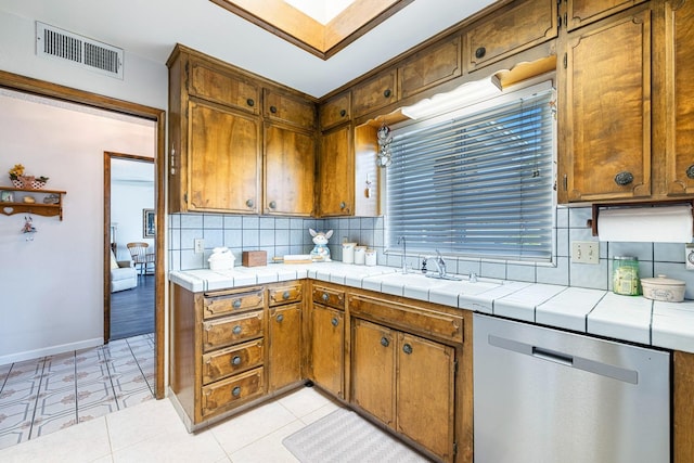 kitchen with decorative backsplash, brown cabinetry, visible vents, dishwasher, and baseboards