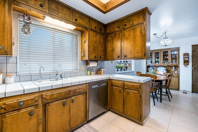 kitchen featuring light tile patterned flooring, brown cabinets, tasteful backsplash, a sink, and dishwasher