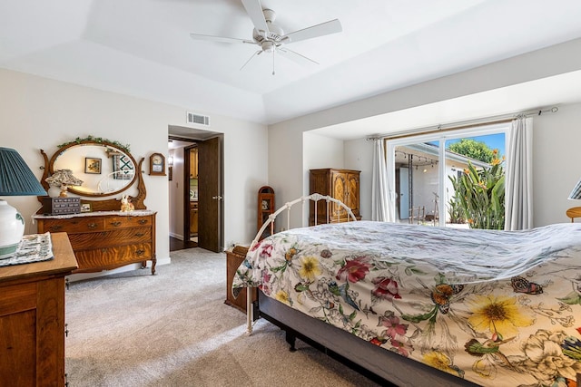 bedroom with a ceiling fan, visible vents, light colored carpet, a raised ceiling, and access to outside