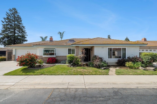ranch-style home featuring an attached garage, a tile roof, stucco siding, a front yard, and a chimney