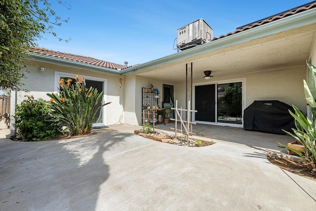 doorway to property with a patio, a tile roof, and stucco siding