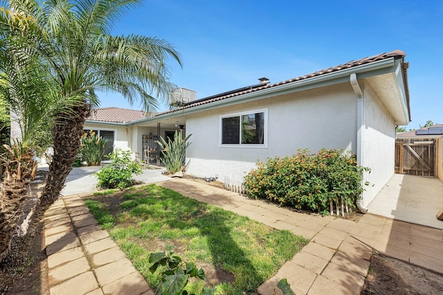view of front of property featuring stucco siding, a tile roof, and fence