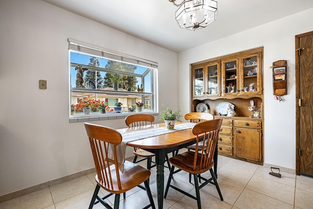 dining room featuring light tile patterned flooring, baseboards, and a notable chandelier