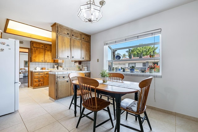 dining space featuring baseboards, light tile patterned floors, and a chandelier