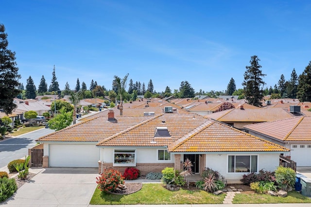 ranch-style home with a tile roof, a residential view, concrete driveway, an attached garage, and stucco siding