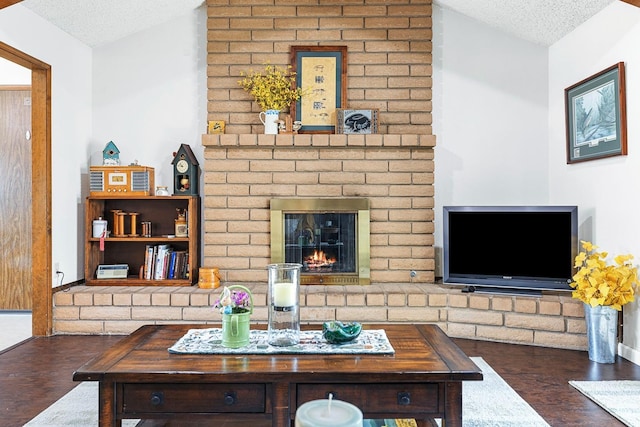 living area with a textured ceiling, a brick fireplace, wood finished floors, and lofted ceiling