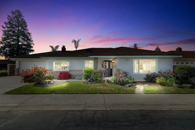 943 E Goshen Ave, Fresno, CA 93720 - ranch-style house with a chimney, stucco siding, a garage, a front lawn, and driveway