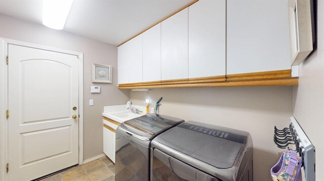 washroom featuring a sink, baseboards, washing machine and dryer, and cabinet space