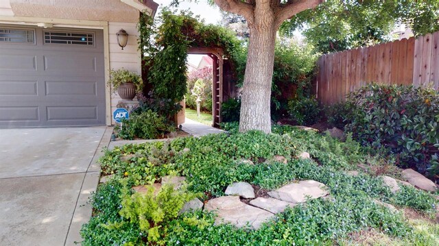 view of yard with concrete driveway and fence