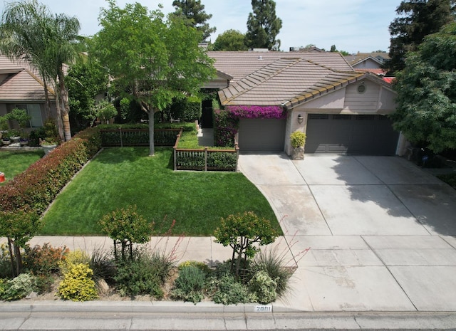 view of front of property with a tiled roof, driveway, a front lawn, an attached garage, and stucco siding