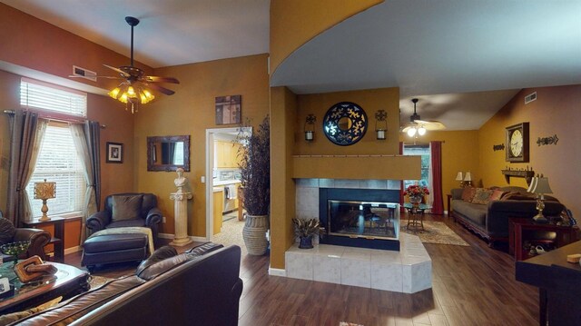 living room with visible vents, lofted ceiling, wood finished floors, a fireplace, and ceiling fan