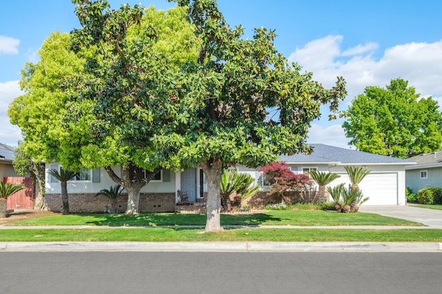 6352 N Fisher St, Fresno, CA 93710 - obstructed view of property featuring driveway, an attached garage, a front yard, and brick siding