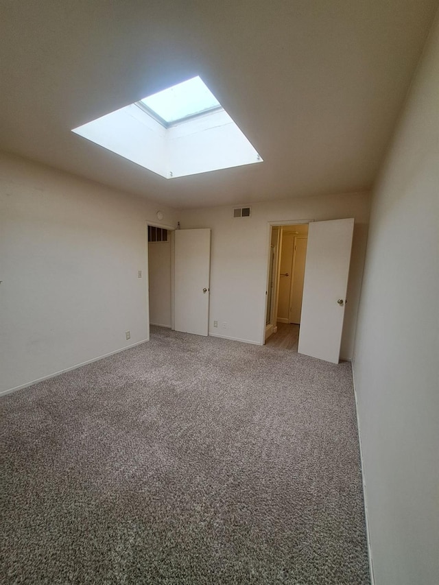 interior space with a skylight, visible vents, light carpet, and baseboards
