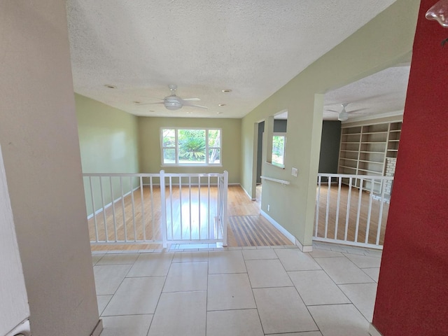 spare room featuring a ceiling fan, a textured ceiling, and tile patterned floors
