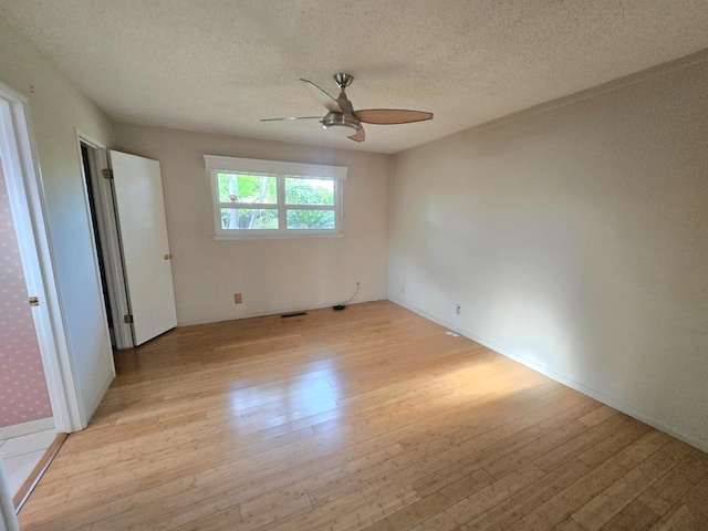 unfurnished bedroom with light wood-type flooring, a ceiling fan, a textured ceiling, and visible vents