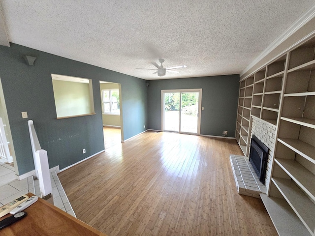 unfurnished living room featuring a brick fireplace, a textured ceiling, ceiling fan, and hardwood / wood-style flooring