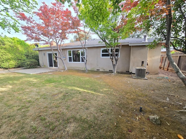 back of property with fence, stucco siding, central AC unit, a patio area, and a yard