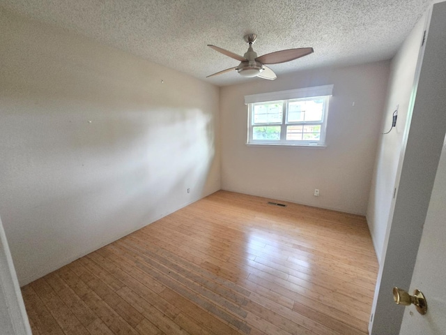 spare room with a ceiling fan, hardwood / wood-style flooring, a textured ceiling, and visible vents